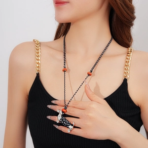 Detail of woven rope necklace featuring a ceramic dachshund pendant and orange bead accents
