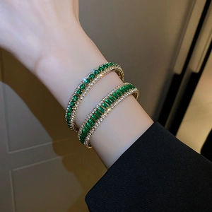 Macro detail of gold-plated bracelet with emerald-cut green stone and zircon inlay