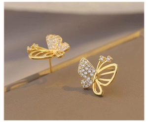 Close-up of golden butterfly earrings with sparkling cubic zirconia and hollow design
