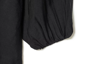 Detailed close-up of elastic cuffs and woven fabric texture on a black V-neck dress