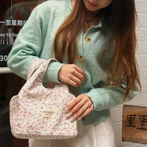 Detail of floral canvas lunch bag with brand label and sturdy handheld handle