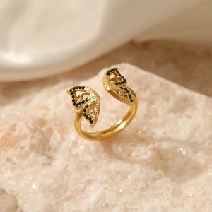 Adjustable gold butterfly ring with black zircon wings on white stone background