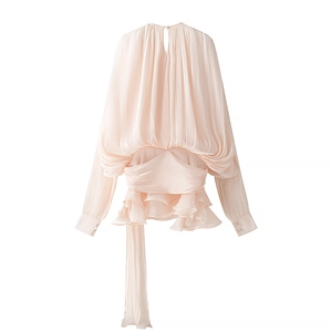 Macro detail of pink pleated fabric with ruffled hem and long ribbon tie on back
