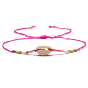 Detailed macro shot of handmade shell bead bracelet with adjustable magenta cord