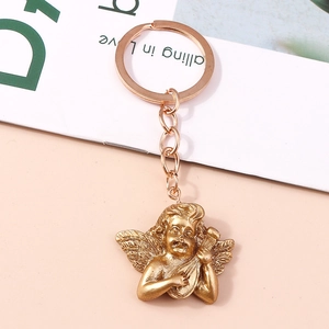 Detailed close-up of golden Cupid angel keychain with wings and musical instrument
