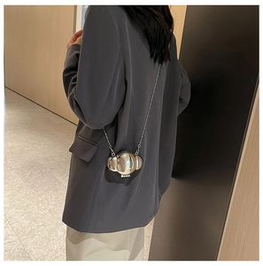 Silver metallic cloud-shaped mini bag worn with a chain strap over a grey blazer