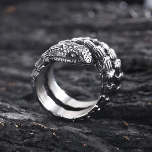 Macro shot of silver coiled snake ring showing metallic texture on rustic bark surface
