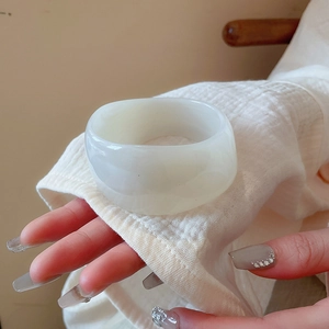 Close-up of a wide irregular white resin bangle on wrist with a minimalist fashion style