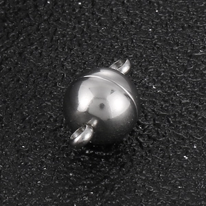 Close-up of spherical stainless steel magnetic clasps for DIY jewelry on black texture