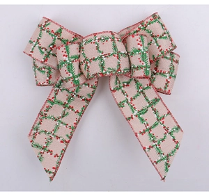 Detail of burlap Christmas bow with green pine needle and red berry print pattern
