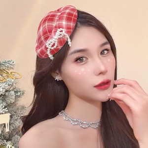 Detail of red plaid hat hair clip featuring pearl bow and festive holiday styling