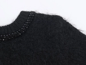 Detail of beaded neckline on black plush knit sweater showing high quality craftsmanship