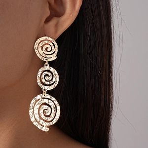 Gros plan de boucles d'oreilles spirales évidées dorées sur mannequin au style rétro