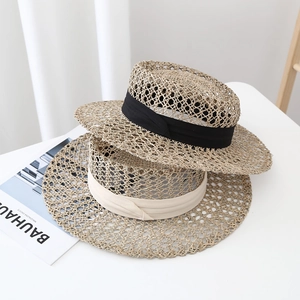 Flat top seagrass straw hats with black and beige ribbons in a hollow weave design