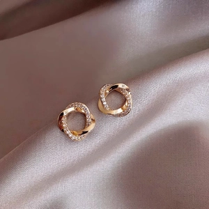 Macro shot of gold twisted double hoop earrings with pavé rhinestones on silk