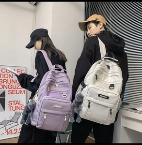 Vista posteriore di zaini scolastici viola e bianchi con tasche e ciondoli carini
