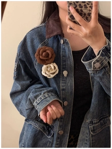 Detail of brown velvet and pearl white camellia flower brooches pinned on a denim jacket