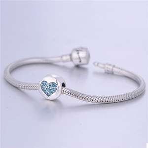 Detalle de pulsera cadena de serpiente plata con abalorio de corazón cristal azul