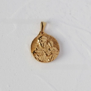 Macro detail of 18K gold plated snake chain pendant with religious relief carving