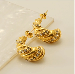 Gros plan de boucles d'oreilles dorées avec incrustation de zircones et texture spirale chic