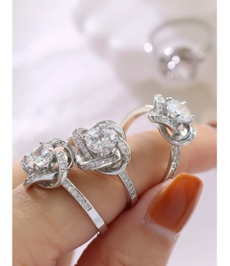 Détail de trois bagues en argent serties de zircons avec motifs floraux sur doigt