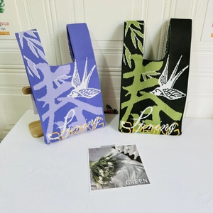 Close-up of purple and black knit tote bags featuring white swallow patterns and Spring text