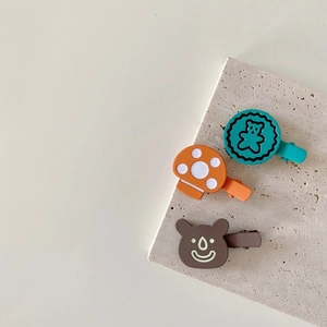 Cute metal bear and mushroom hair clips for kids on a minimalist stone background