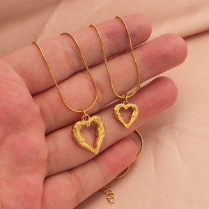 Close-up of gold heart pendants with angel wings on delicate snake chains for couples