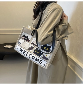 Detail of canvas tote bag featuring cute cat illustrations and Welcome text on shoulder