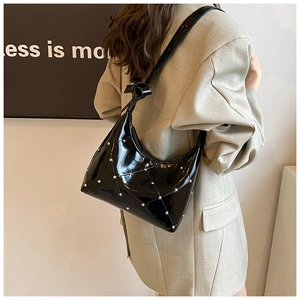 Détail du sac croissant en cuir verni noir avec matelassage losange et clous argentés