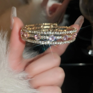 Macro detail of multilayer gold bracelet with pink stones and zircons on fur