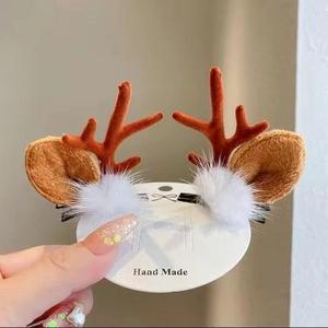 Close-up of reindeer antler hair clips with brown fur and white plush balls for Christmas