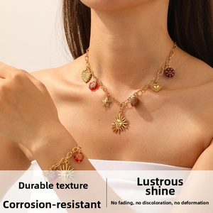 Détail du parure collier à breloques soleil et cœur vintage doré avec perles fleurs rouges