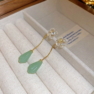 Detailaufnahme goldener Quastenohrringe mit jadegrünen Tropfen und kleinen Kristallblumen
