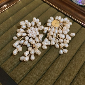Detail of handcrafted floral pearl cluster earrings on a vintage green velvet tray