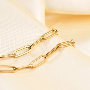 Minimalist 14K gold plated paperclip link bracelet on elegant beige satin fabric