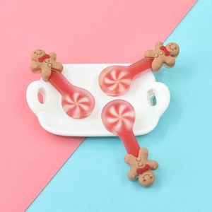 Close-up of three gingerbread man resin spoons with red and white candy swirl patterns