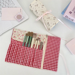 Detailed view of floral and plaid fabric makeup brush roll bags for portable storage