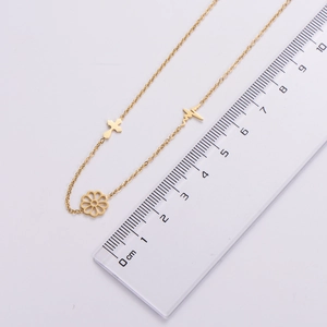 Detailed view of a gold flower necklace pendant with a ruler for precise size reference