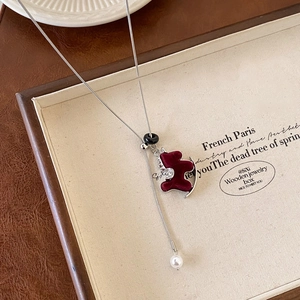 Detail of vintage burgundy flocked bear pendant and pearl on silver necklace chain