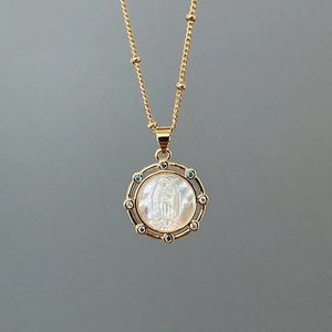 Macro shot of gold portrait necklace with mother of pearl and inlaid zircon detail