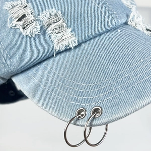 Detailansicht der hellblauen Denim-Baseballkappe mit Distressed-Löchern und Metallringen