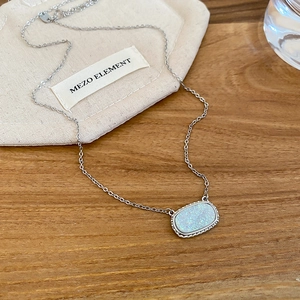 Detail of silver chain with oval iridescent faux opal pendant on a wooden surface