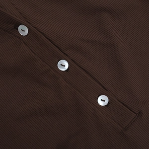 Close-up of dark brown ribbed knit fabric with white pearl buttons on a stylish cardigan
