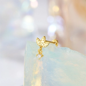 Macro shot of gold clover piercing stud with hanging clear zircon on crystal stone