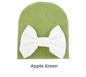Detail of lime green infant beanie with white bow ornament and soft knitted texture