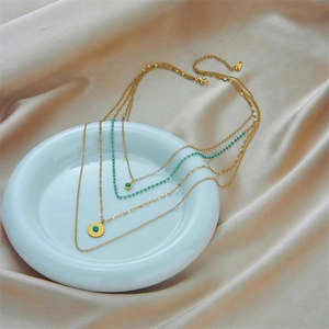 Layered gold titanium steel necklace featuring turquoise beads and circular pendant charms