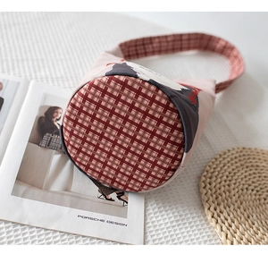 Detail of fabric bucket bag featuring brown plaid pattern and sturdy cylindrical base