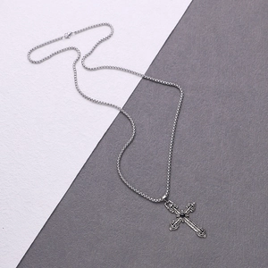 Detail of silver vintage cross pendant featuring a black gemstone on a box chain
