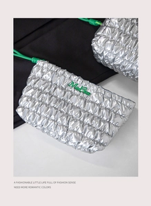 Close-up of silver quilted texture with a green logo on a luxury drawstring cosmetic bag